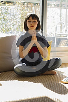 Relaxed child practicing a yoga namaste for happiness and wellbeing