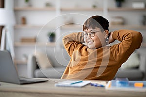Relaxed asian boy looking at notebook screen and smiling