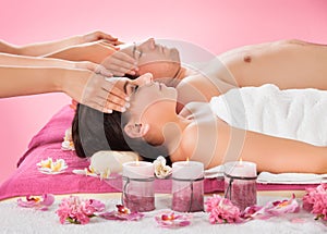 Relaxed couple receiving head massage at spa