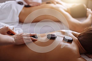 Relaxed Couple Receiving Hot Stone Therapy At Beauty Spa