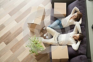 Relaxed couple resting on couch after moving in new home