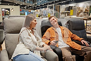 Relaxed couple sitting at comfortable armchair enjoying shopping time