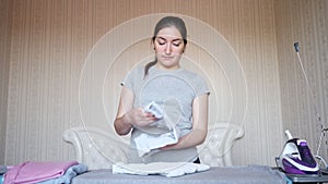 Relaxed dark haired housewife stacks clothes after ironing