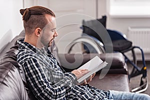 Relaxed disabled man reading on the couch