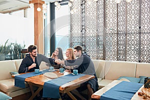 Relaxed diverse friends in bathrobes sitting at lounge zone of bathhouse