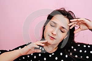 Relaxed, dozed out young woman. Her eyes closed, she's touching her face