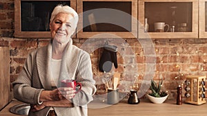 Relaxed Elderly Woman With Cup Of Coffee Posing In Kitchen