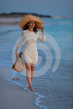 Relaxed elegant woman on seacoast at sunset walking
