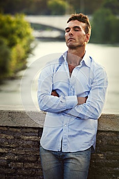 Relaxed eyes closed man on bridge outdoors in Rome Italy. Tiber river