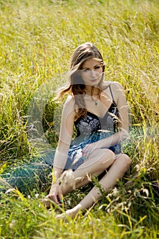 Relaxed fashion woman sitting in sunny field