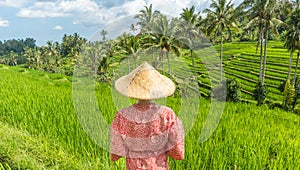 Relaxed fashionable caucasian woman wearing red asian style kimono and traditional asian paddy hat looking at beautiful