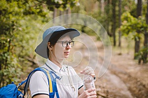 Relaxed female tourist resting in nature. Happy woman tourist with backpack. tourist girl drinking water in forest. Female with