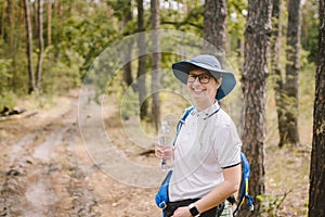 Relaxed female tourist resting in nature. Happy woman tourist with backpack. tourist girl drinking water in forest. Female with