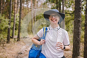 Relaxed female tourist resting in nature. Happy woman tourist with backpack. tourist girl drinking water in forest. Female with