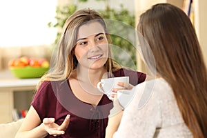 Relaxed friends talking and drinking at home photo