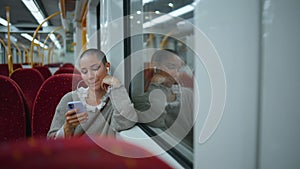 Relaxed girl commuting train listening music by earbuds. Woman sitting railway