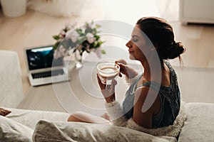 Relaxed girl at home drinking coffee.Inner peace.The girl is sitting comfortably on the sofa and drinking coffee
