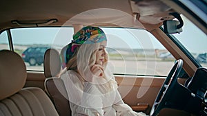 Relaxed girl sitting auto in colorful bandanna close up. Blonde posing retro car