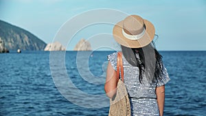 Relaxed girl in straw hat and sunglasses contemplate seascape at sunset. Shot with RED camera in 4K