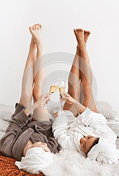 Relaxed girlfriends laying with legs up and drinking champagne