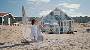 Relaxed girls taking selfie at ocean shore. Joyful lesbian couple resting beach