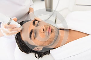 Relaxed guy getting electric facial massage