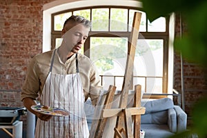 Relaxed happy 40s man painting in art studio.