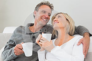 Relaxed happy couple with coffee cups in living room