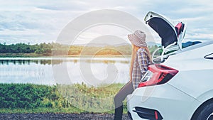 Relaxed happy woman traveler on summer roadtrip vacation on hatchback car