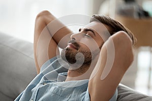 Relaxed happy young man resting having nap on comfortable couch