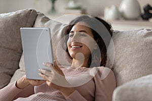 Relaxed happy young woman using digital computer tablet.