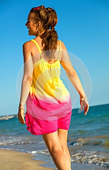 Relaxed healthy woman in colorful dress on seacoast in evening