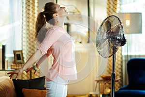Relaxed housewife enjoying freshness in front of working fan