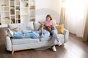 Relaxed indian couple on couch with phone enjoying home time