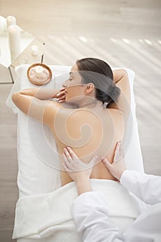 Relaxed indian woman enjoying back massage in spa salon, top view