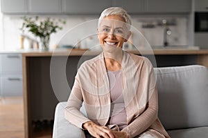 Relaxed and joyful senior woman sitting on sofa at home