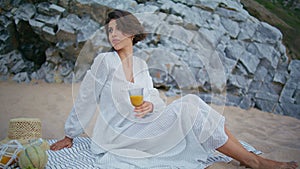 Relaxed lady enjoying picnic on ocean beach. Elegant romantic model rest shore