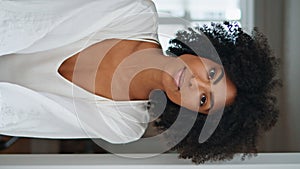 Relaxed lady looking window at weekend morning. Dark skin woman resting vertical