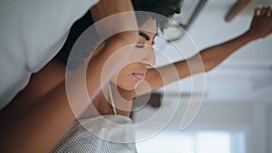 Relaxed lady stretching at morning bed closeup. African serene girl waking up