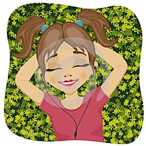 Relaxed little girl lying on grass listening to music outdoors with eyes closed