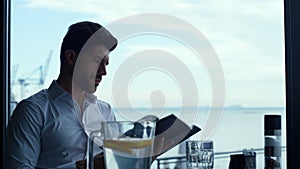 Relaxed man customer reading wine list in panoramic luxury lounge bar portrait