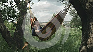 Relaxed man enjoying vacation in hammock at green garden. Young male in hammock at summer sunny day. Casual man relax on hammock o