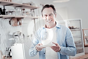 Relaxed man feeling glad while getting a cup of coffee