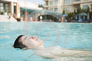 Relaxed man floating in the pool with eyes closed