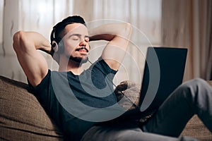 Relaxed Man Listening to Music on His Laptop at Home