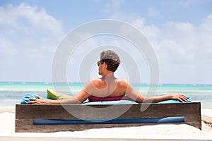 Relaxed man in luxury lounger enjoying summer vacations on beautiful beach.