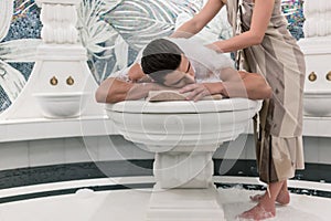Relaxed man lying down on hot marble bed during traditional Turkish bath