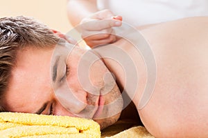 Relaxed man receiving acupuncture treatment in spa