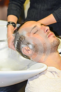 Relaxed man shampooed by his hairdresser