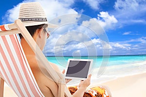 Relaxed man sitting on beach chairs and touching tablet